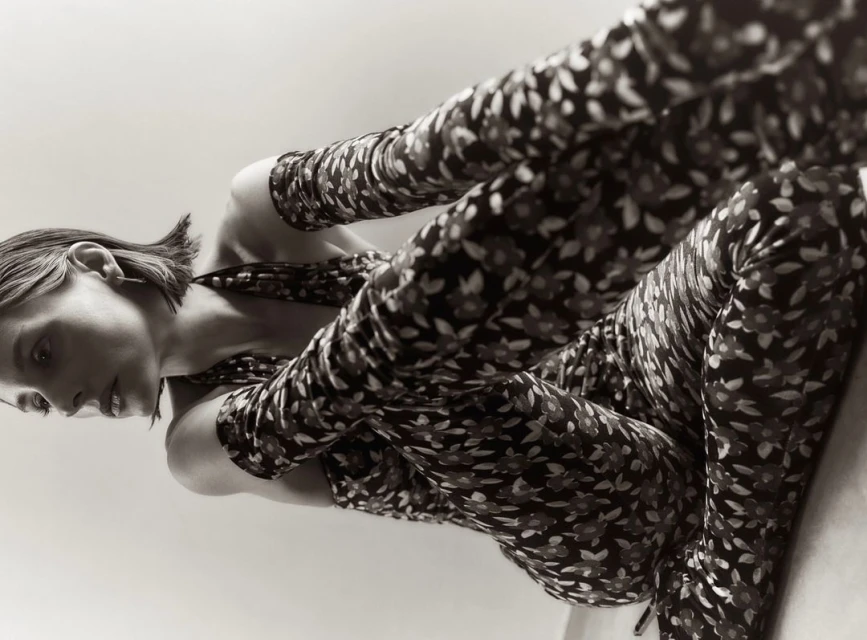 Low-angle shot of a young woman in a floral-patterned jumpsuit, lying down and looking to the side, showcasing a unique perspective.