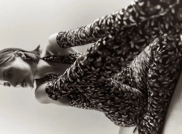 Low-angle shot of a young woman in a floral-patterned jumpsuit, lying down and looking to the side, showcasing a unique perspective.