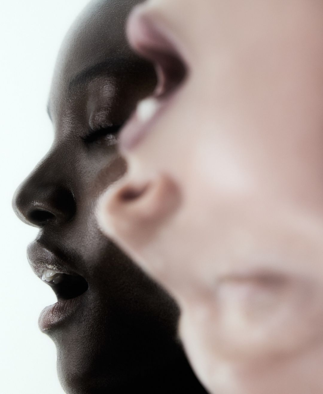 Close-up abstract portrait of two models side-by-side with overlaid profile features against a white background