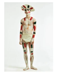 Full-length portrait of a man wearing body paint and a wide-brimmed hat against a plain white studio background.
