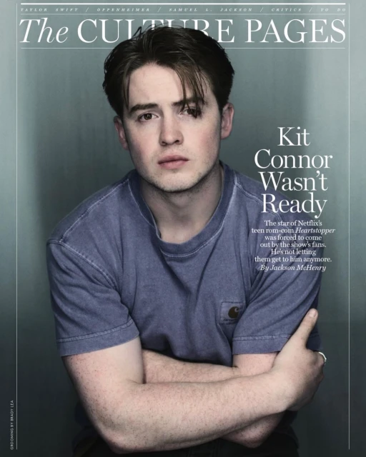 Portrait of Kit Connor on the cover of The Culture Pages, wearing a blue t-shirt, arms crossed, against a gradient grey background.