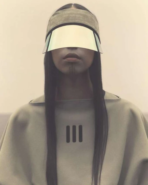 Close-up studio shot of a person with long black hair, wearing a visor and a light tan top with vertical stripes design.