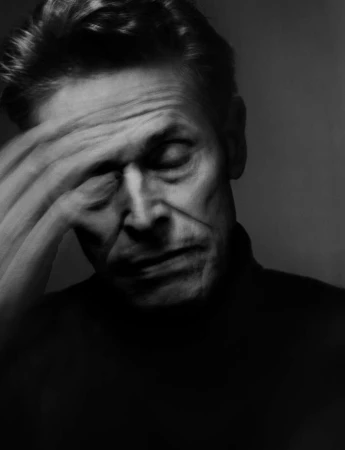 Portrait of Willem Dafoe with hand to forehead in dark moody lighting by Nadav Kander