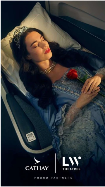 A woman in a gown with a crown sleeping on an airplane, illuminated by warm lighting, holding a red rose in her hand.
