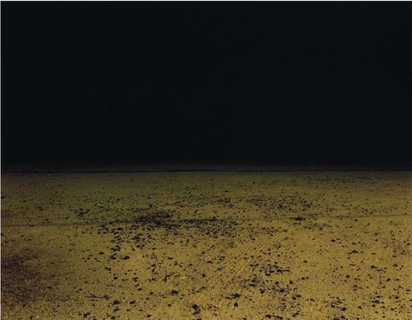 Abstract landscape with a dark sky over a textured, golden field, creating a sense of depth and desolation in an outdoor scene.