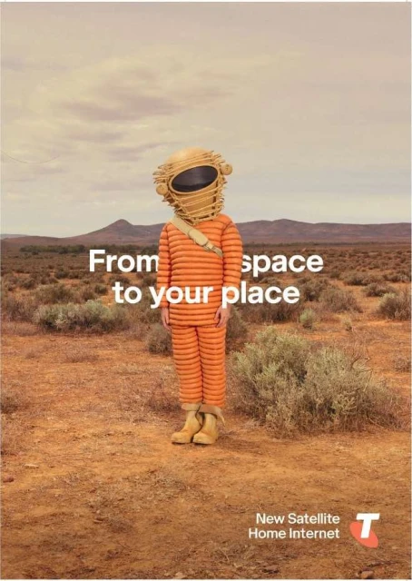 Person in an orange suit and helmet stands in a desert landscape. Advertising image promoting satellite internet.