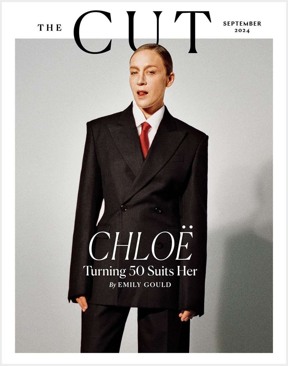 Chloe Sevigny on the cover of The Cut magazine, September 2024 issue. She is wearing a black oversized suit and a red tie.