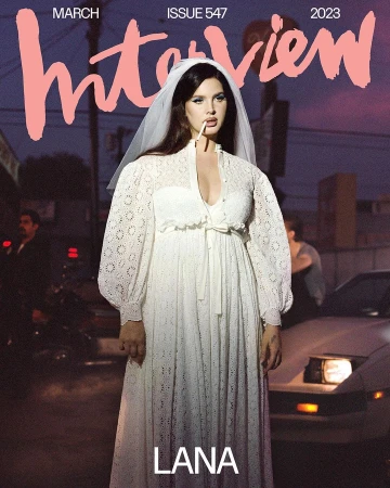 Lana Del Rey, Interview Magazine cover, March 2023. Woman in white dress with cigarette, posing by car on street at twilight.