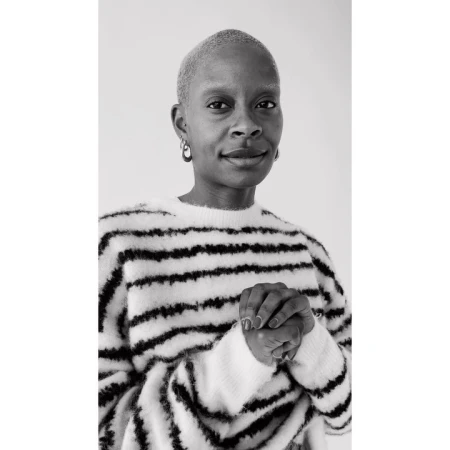 Black woman with short buzzcut wearing a striped sweater, captured in a monochrome portrait.