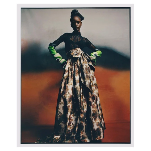 Elegant high-fashion portrait of a Black model wearing a long flowing skirt and black lace top in a studio with mottled backdrop.