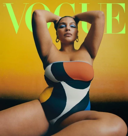 Model wearing a colour-blocked strapless swimsuit with blue eyeshadow against a warm gradient background