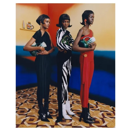 Three black female models in patterned clothing pose indoors holding jugs. The scene features vibrant color blocking and retro styling.