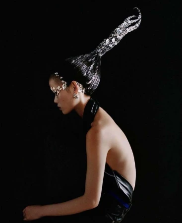 Glamour shot of a woman with jeweled hair, wearing a black top against a dark background, emphasizing beauty and unique hairstyle.
