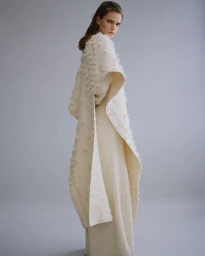 Model in textured white knit wrap and matching dress posing against a grey studio backdrop captured by Nadine Ottawa