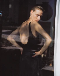Model in a black tank top and dark leather skirt looking back over her shoulder in Milan by Nadine Ottawa.