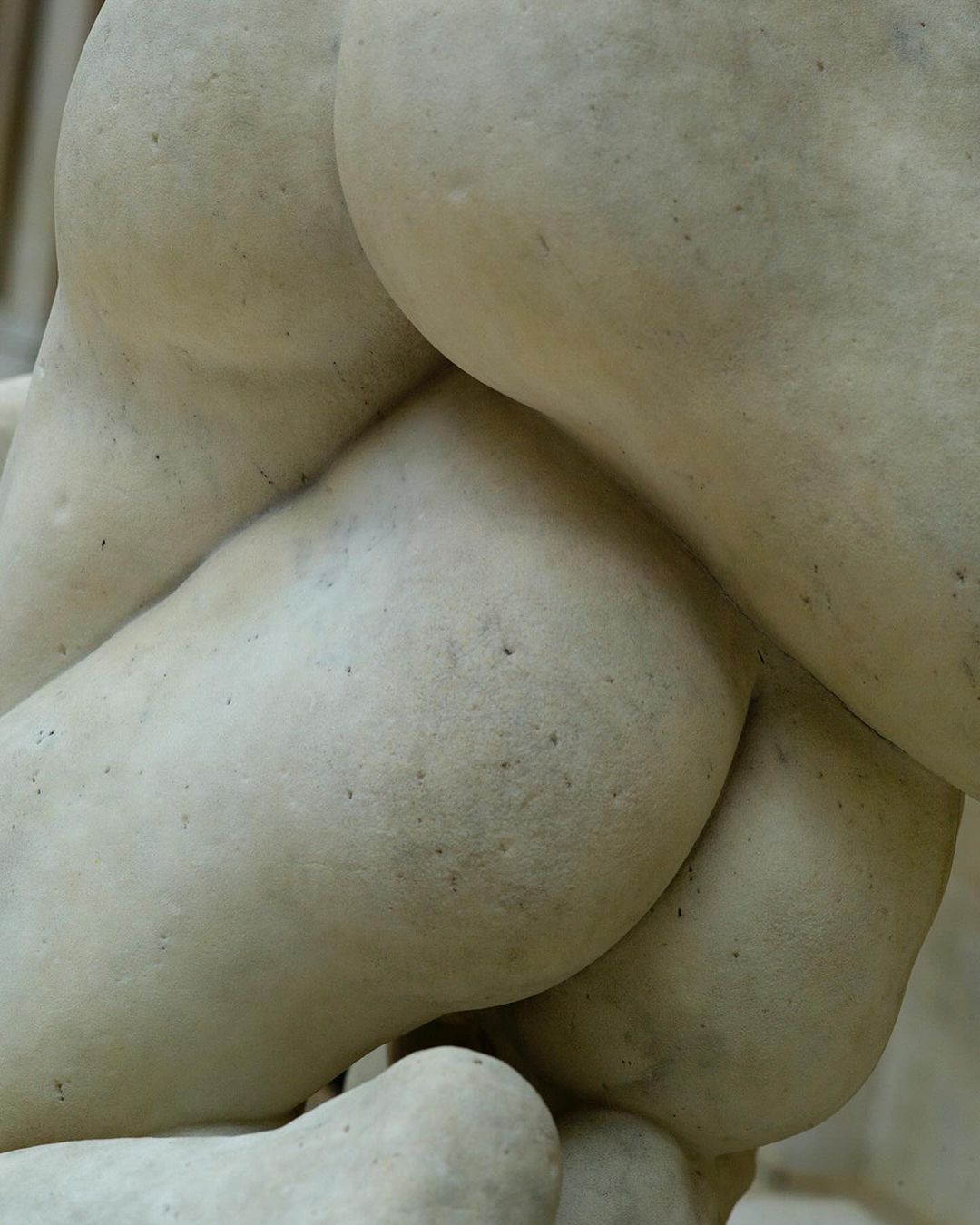 Close-up of a partial female marble statue showcasing the gluteal region with smooth texture and light, neutral color palette.