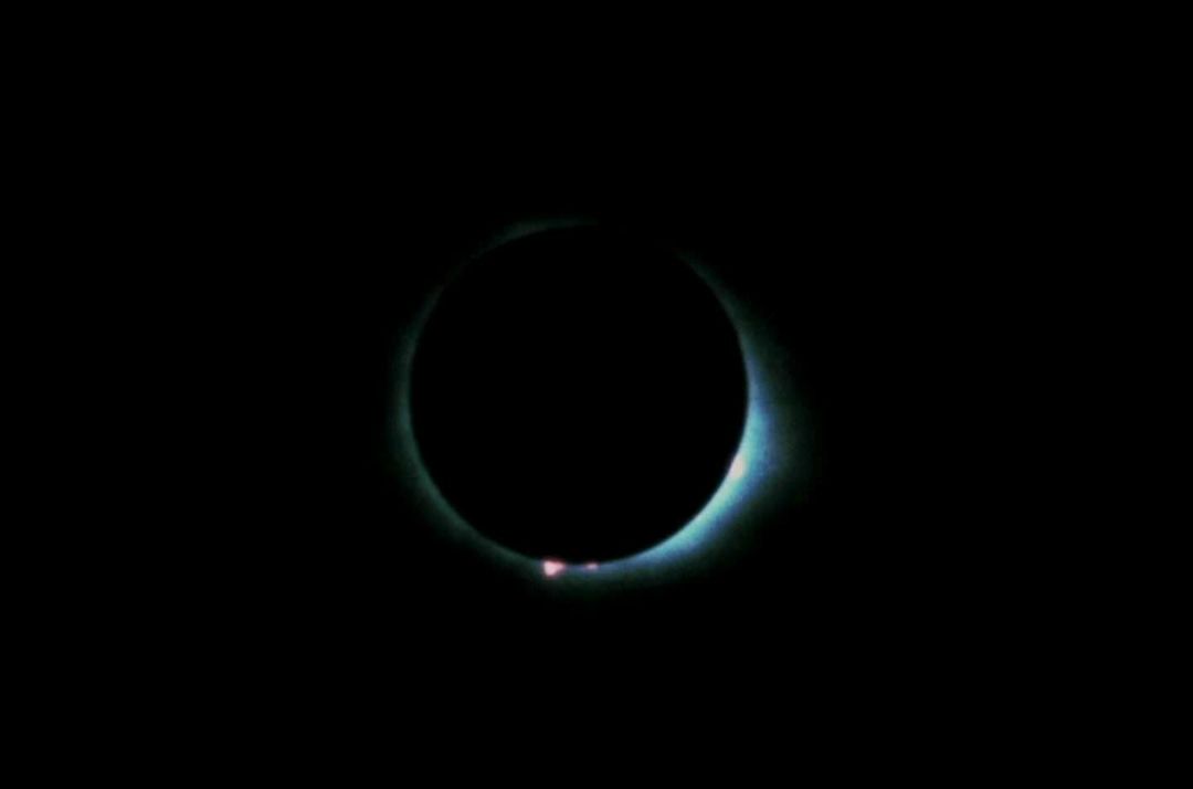 Dramatic wide shot of a total solar eclipse with visible corona effect, set against a pitch-black sky.