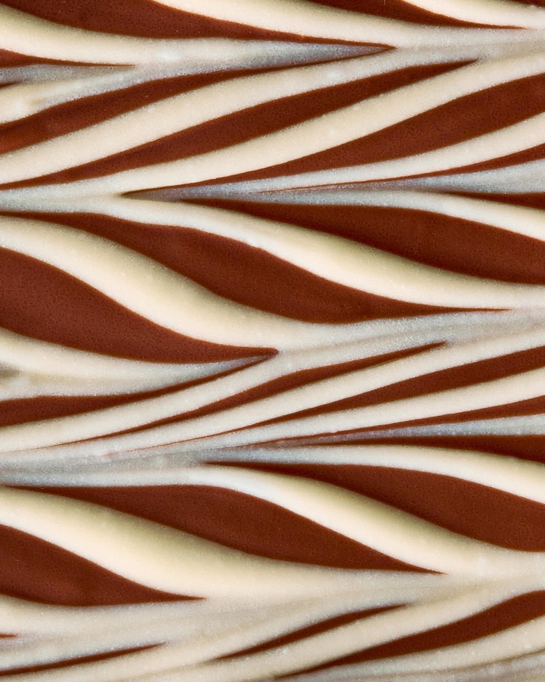 Close-up of a chocolate and cream striped dessert or candy confection forming a diagonal, textured pattern.