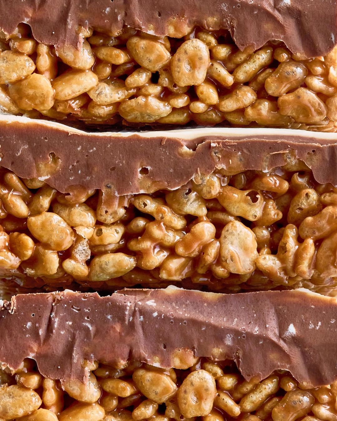 Close-up of a layered rice crispy treat featuring a crispy rice layer and a chocolate layer, stacked and ready to be enjoyed.