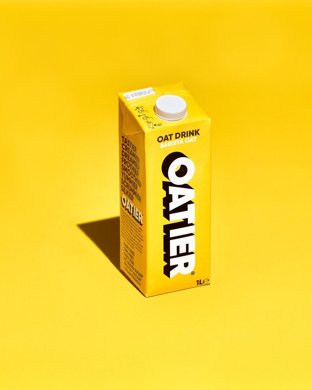 Oattier Barista Oat Drink carton on a bright yellow background, commercial studio shot, beverage, breakfast, oat milk.