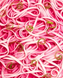 Overhead food photography of vibrant pink noodles garnished with coiled green onion ribbons.