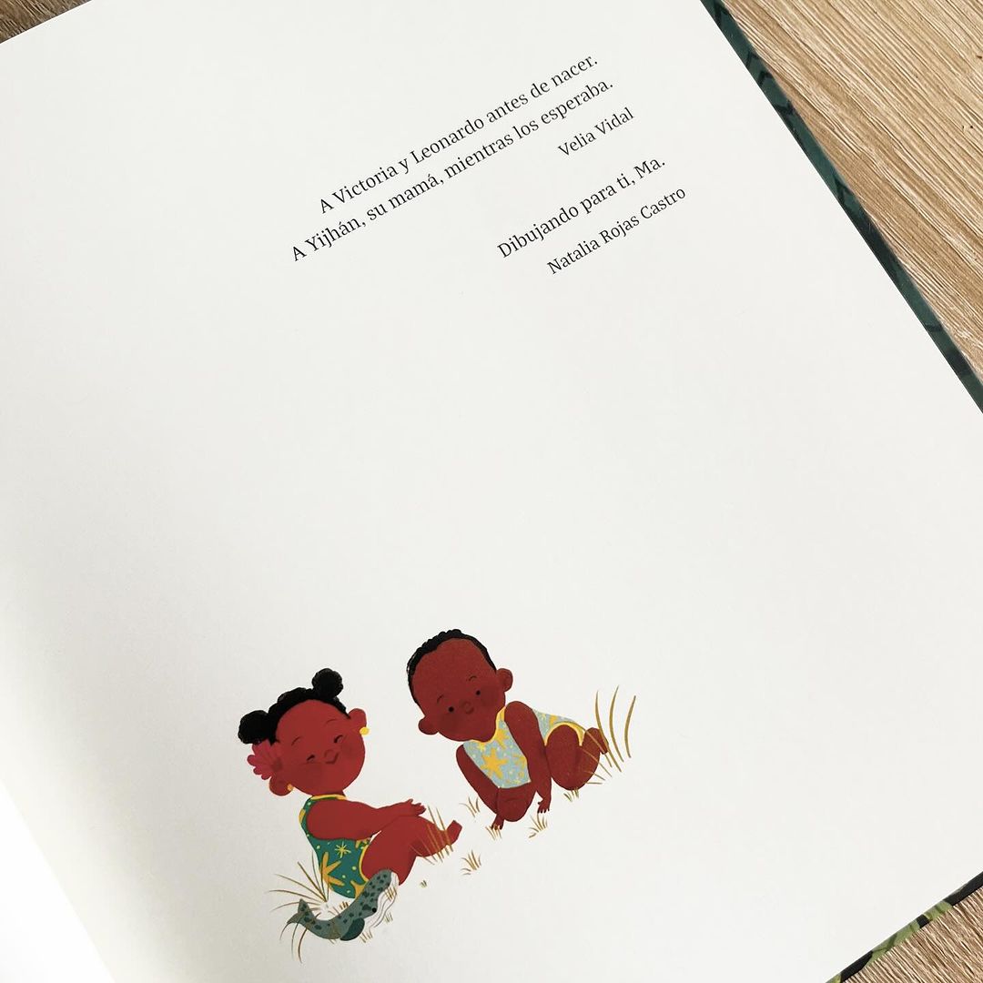 Illustration of two dark-skinned babies sitting on the ground on the pages of a book with text at the top of the page.