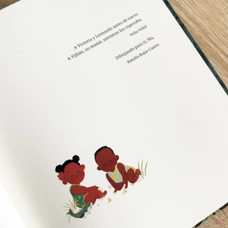 Illustration of two dark-skinned babies sitting on the ground on the pages of a book with text at the top of the page.