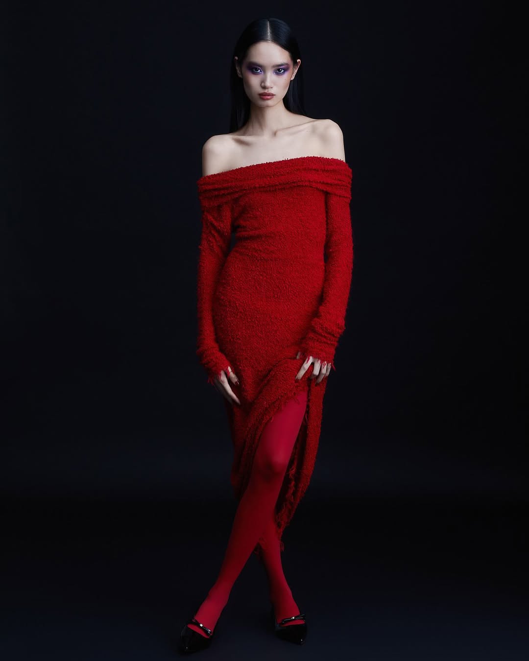 Model wearing a red off-the-shoulder dress and matching red tights against a dark background in Paris by Natasja Fourie.