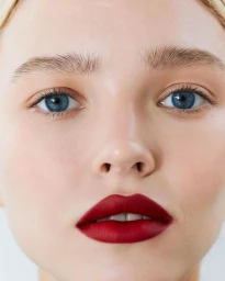 Extreme close-up portrait of a model with vibrant red lipstick and striking blue eyes captured by Natasja Fourie