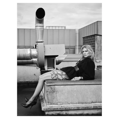 Black and white portrait of a woman reclining on a rooftop ledge next to large industrial ductwork, photographed by Nathaniel Goldberg.