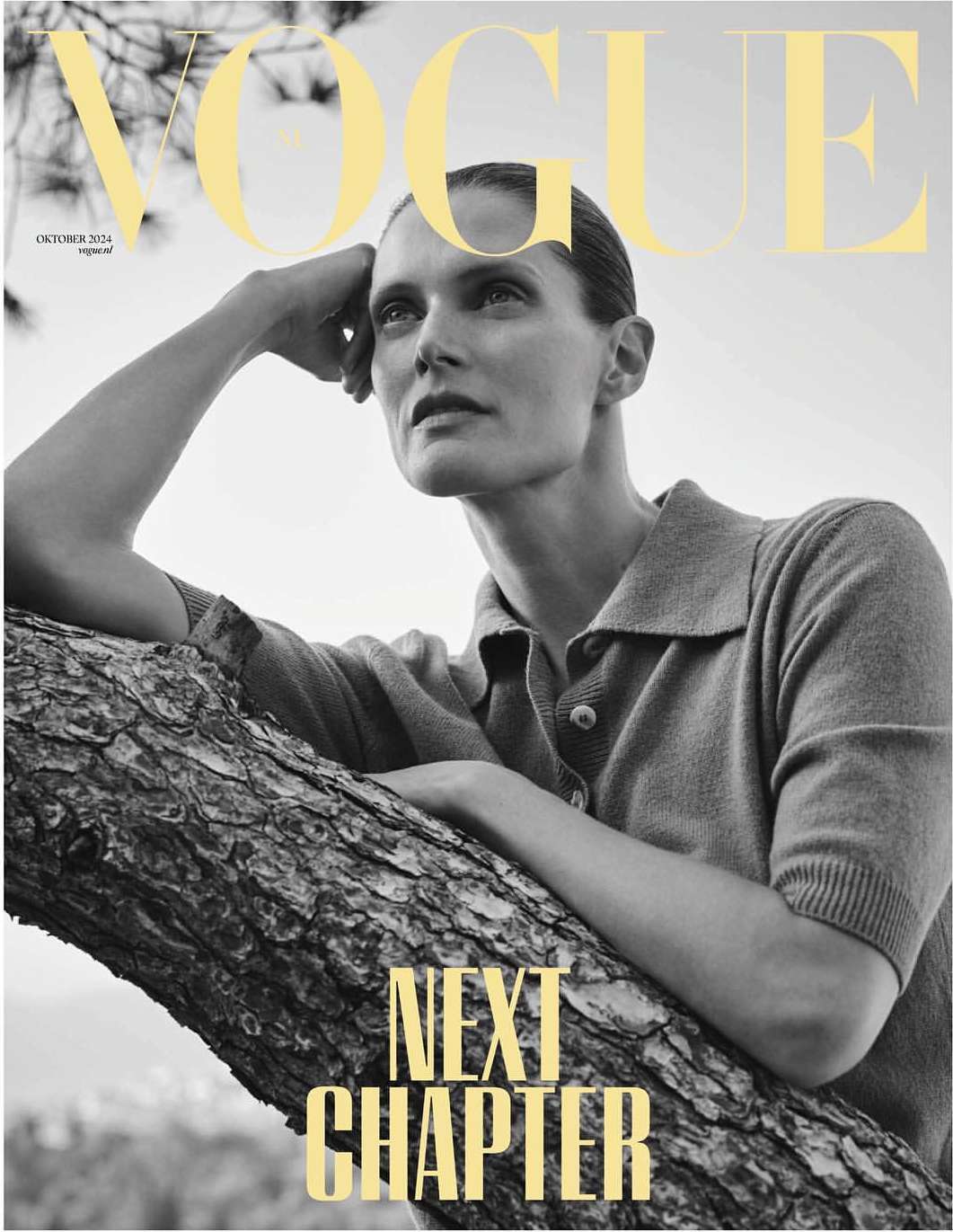 Vogue magazine cover featuring a model in a tan collared shirt resting on a tree branch against a bright, outdoor background.