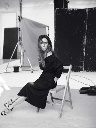 Victoria Beckham seated on a wooden folding chair in a studio by Nathaniel Goldberg