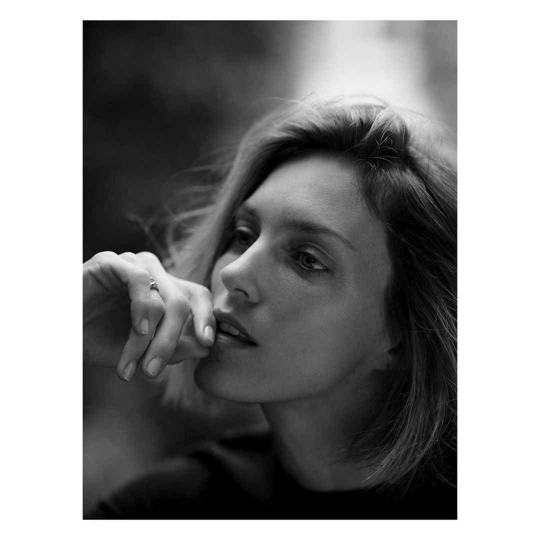 Close up monochrome portrait of a woman with short hair resting her hand near her lips by Nathaniel Goldberg
