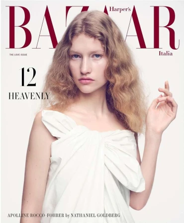 Model with wavy blonde hair wearing a white strapless top against a seamless white background for a magazine cover.