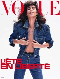 Model wearing a blue denim jacket and matching jeans against a white background for a magazine cover portrait in Paris.
