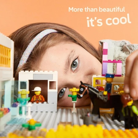 A child plays with a Lego set featuring Lego people, a Lego horse, Lego buildings, and a vibrant color palette, offering a creative scene.