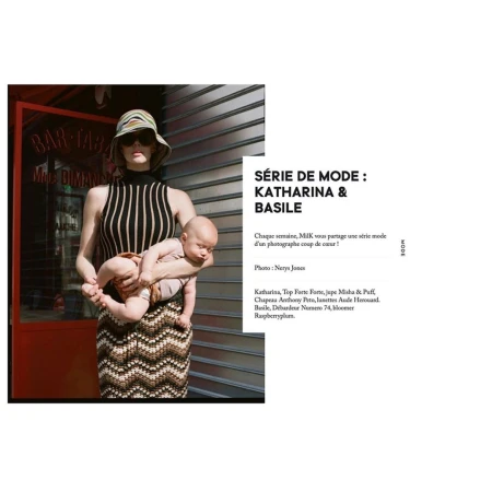 Woman wearing sunglasses and a striped hat holding an infant in an editorial fashion photograph by Nerys Jones