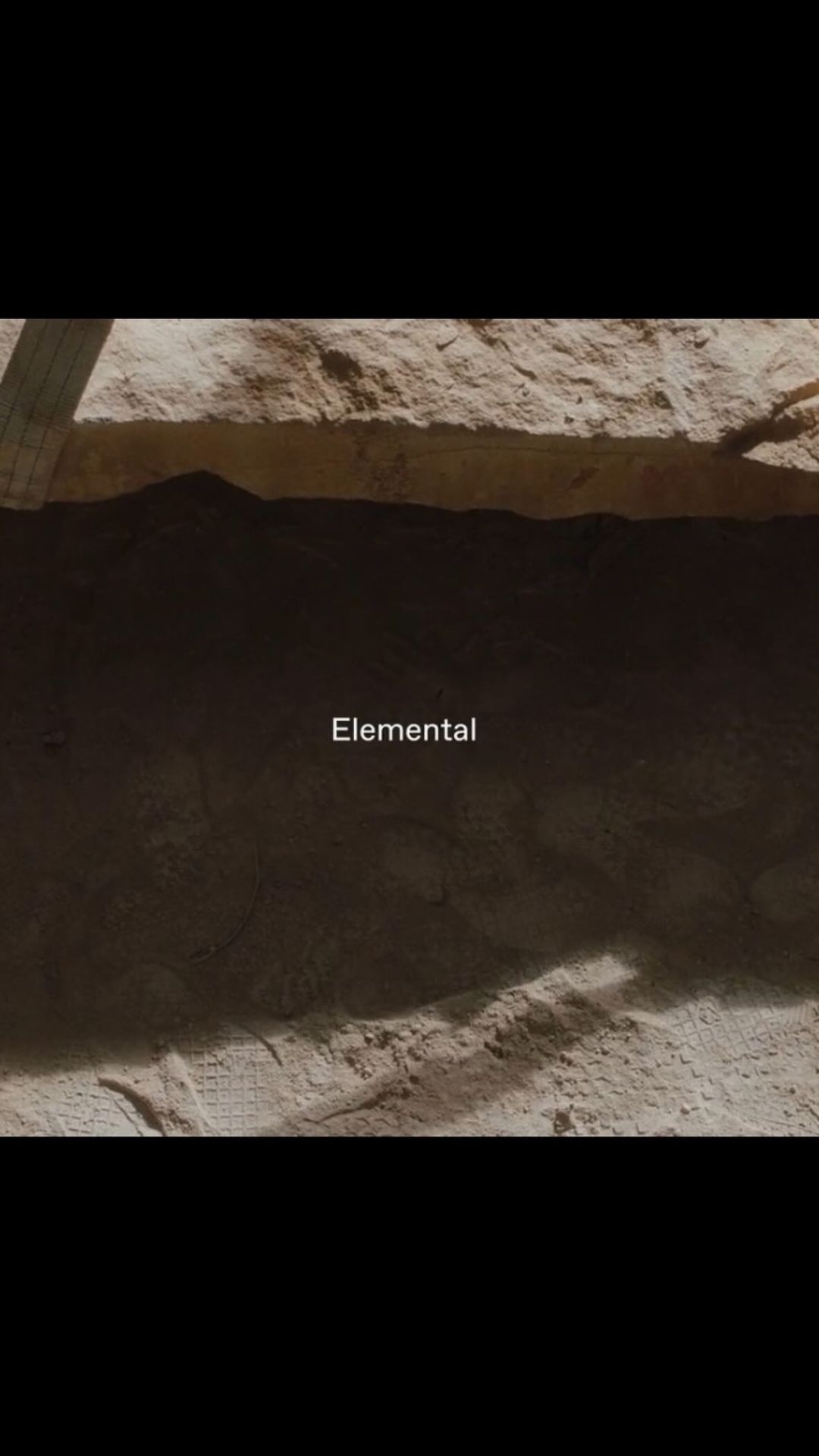 Abstract background featuring a wall or earth formation with a layer of rough rock or soil under diffuse, natural lighting conditions.