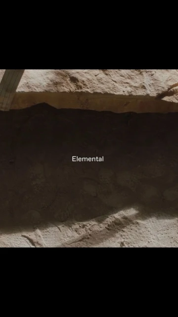Abstract background featuring a wall or earth formation with a layer of rough rock or soil under diffuse, natural lighting conditions.