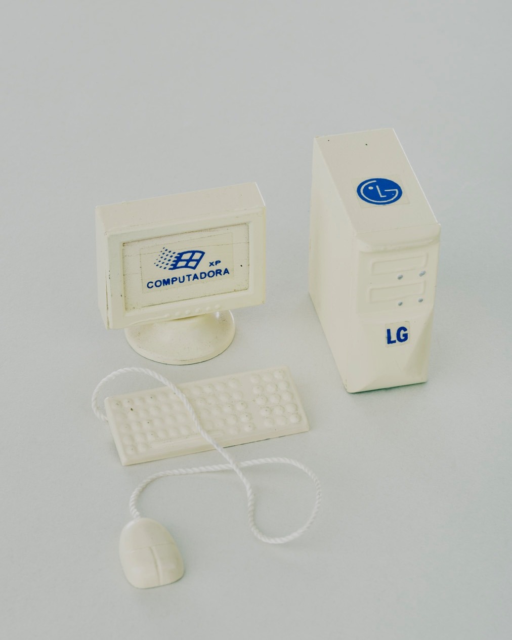 A miniature white computer setup including a monitor, keyboard, mouse, and tower with blue LG and Windows XP logos against a white backdrop.