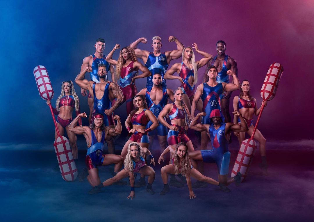 Group portrait of muscular men and women in athletic wear, flexing and posing, set against a blue and purple gradient background.