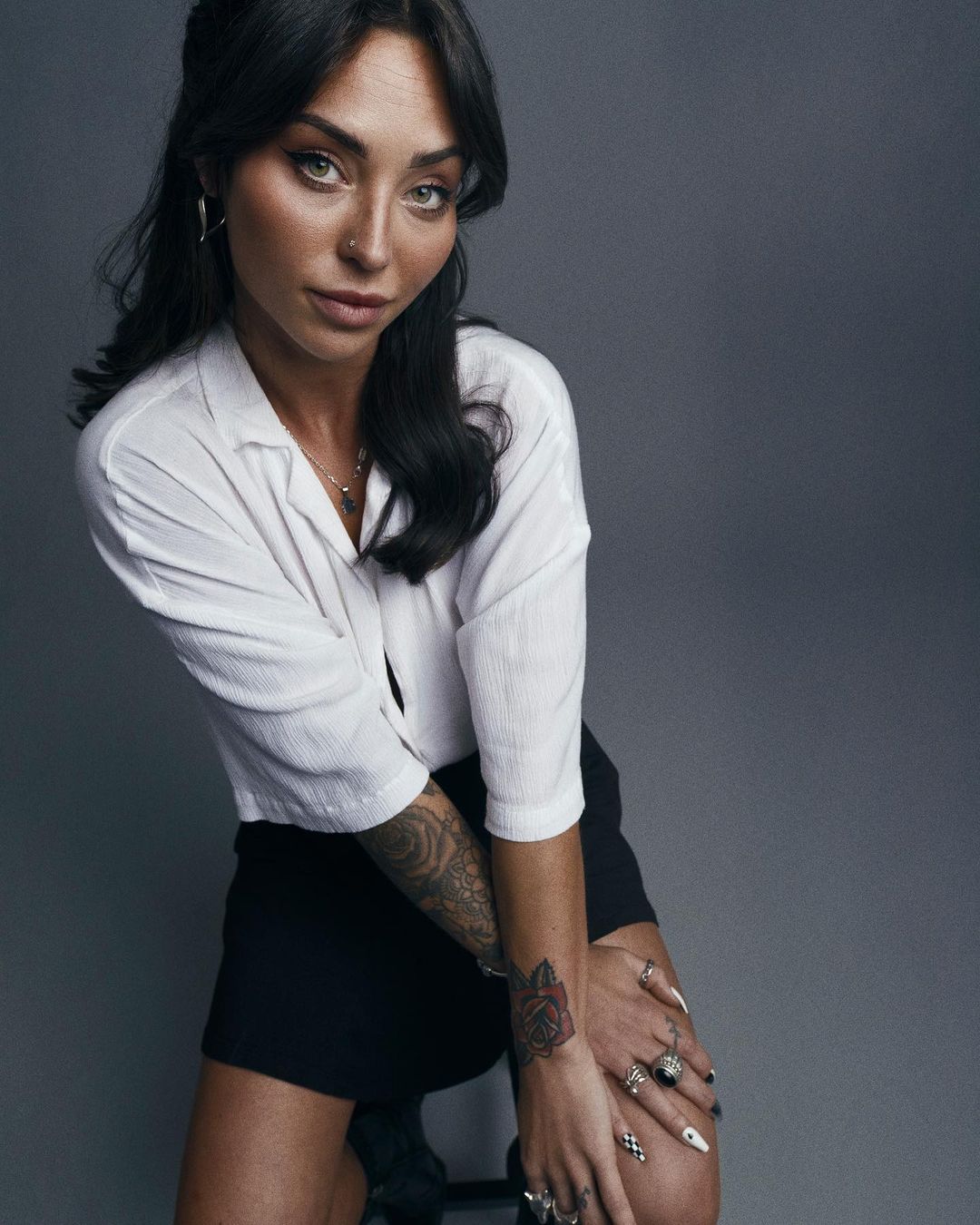 Portrait of a woman wearing a white short-sleeve button-down shirt and black skirt against a grey background by Nick Eagle