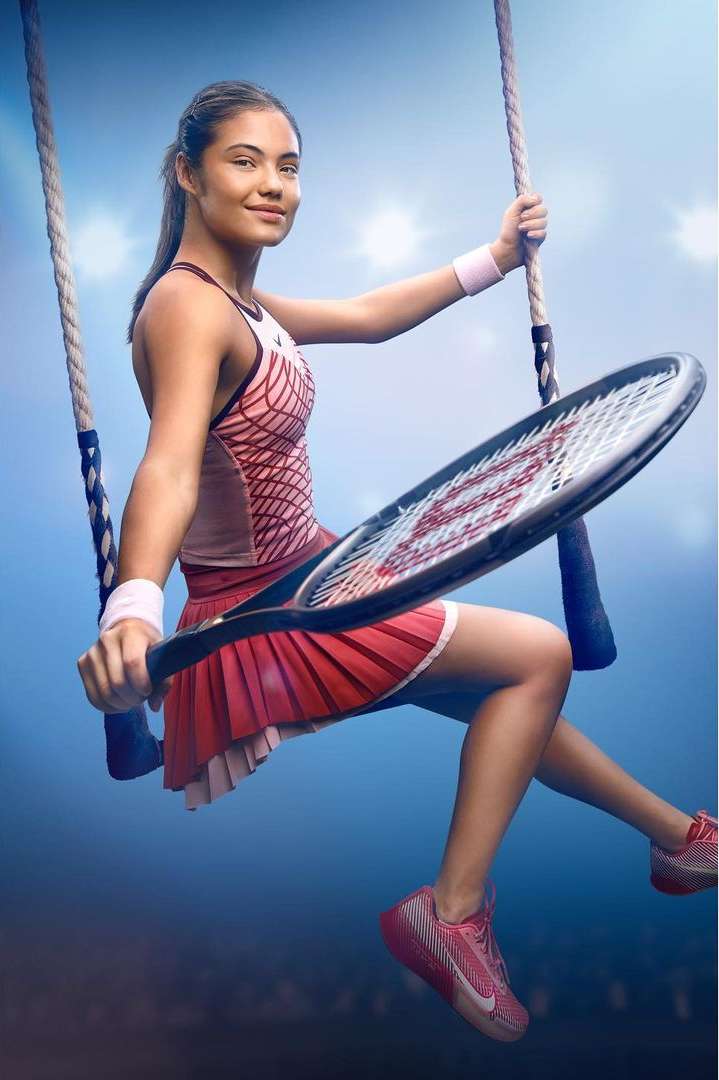A tennis player is sitting on a swing holding a racket and wearing tennis apparel in front of a blue background with lights.