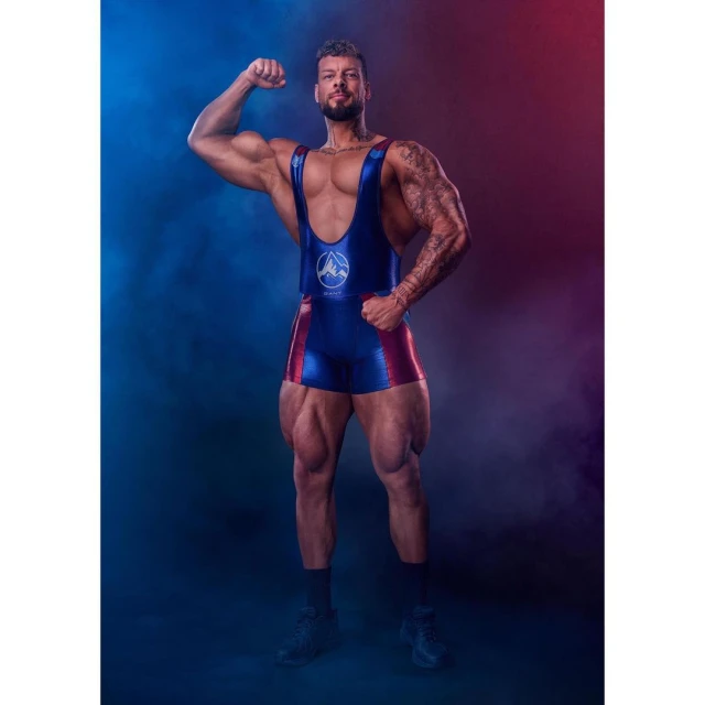 Muscular man in blue and red singlet flexes his bicep against a blue and red gradient background. Fitness and bodybuilding photography.