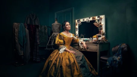 Woman in period costume seated at a vintage vanity table in a dark green dressing room by photographer Nick Eagle