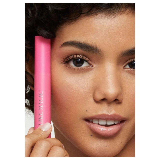 Close-up of a woman's face showcasing mascara in a beauty advertisement, featuring pink packaging and clear skin, with a soft focus.