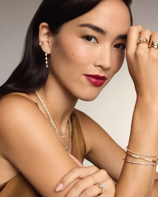 Elegant Asian woman showcases diamond jewelry including earrings, necklace, bracelets, and rings against a neutral background.