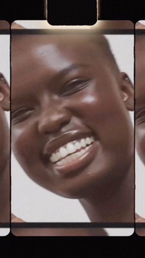 Extreme close-up of a smiling African-American woman's face, showcasing her skin texture, smile, and appearance, framed by a black border.