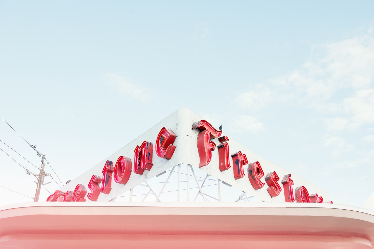 Vintage Firestone sign on a white building against a bright blue sky creates a retro-inspired architectural image.