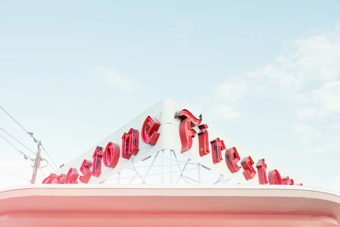 Vintage Firestone sign on a white building against a bright blue sky creates a retro-inspired architectural image.